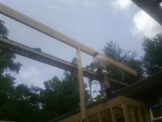 Carpenter setting a ridge beam over a new addition frame — Ice Dam Removal by Roofing Brothers in Yancey