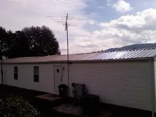 New metal roof on a single wide mobile home with a TV antenna in Yancey