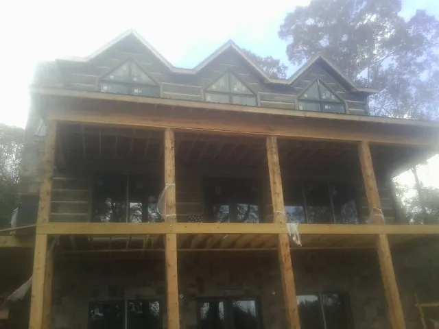 Dormers and porch framing on a large log home under construction — Roof Coating work by our crew in Yancey