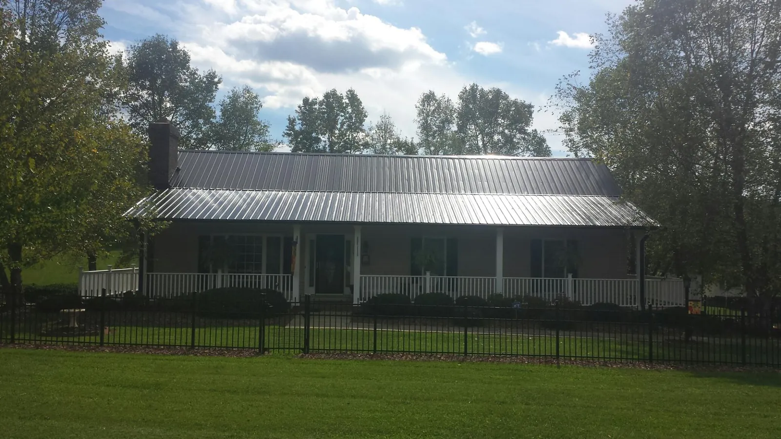 Gray metal roof on a brick ranch with a full width front porch — Gutter Guard Installation work by our crew in Yancey