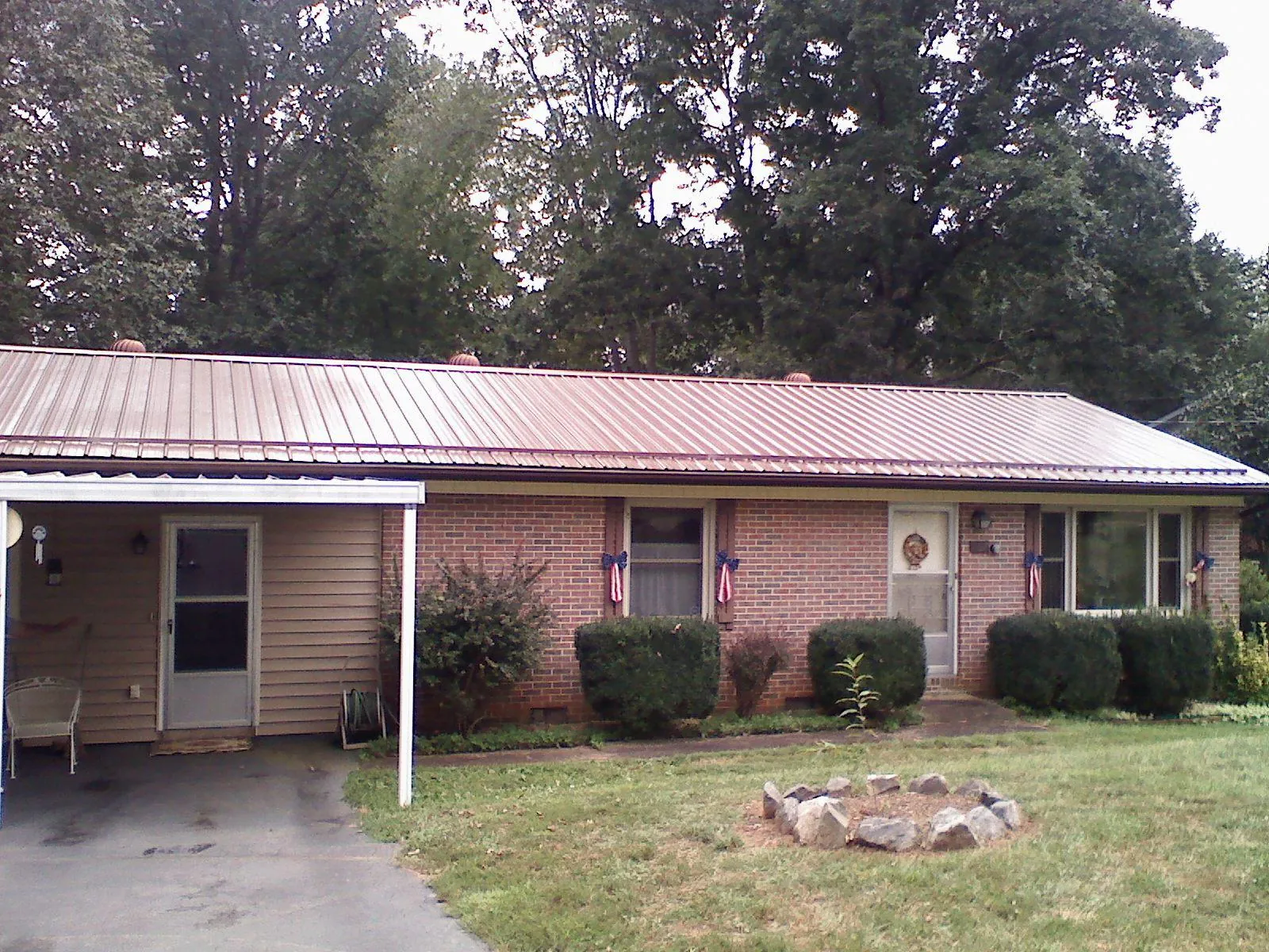 Bronze metal roof and carport on a brick ranch home — Roof Repair work by our crew in Yancey